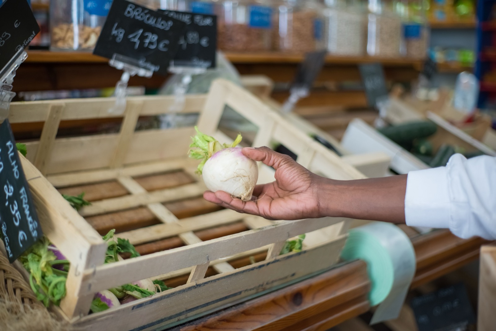 A hand passes an onion across the counter of a small grocery