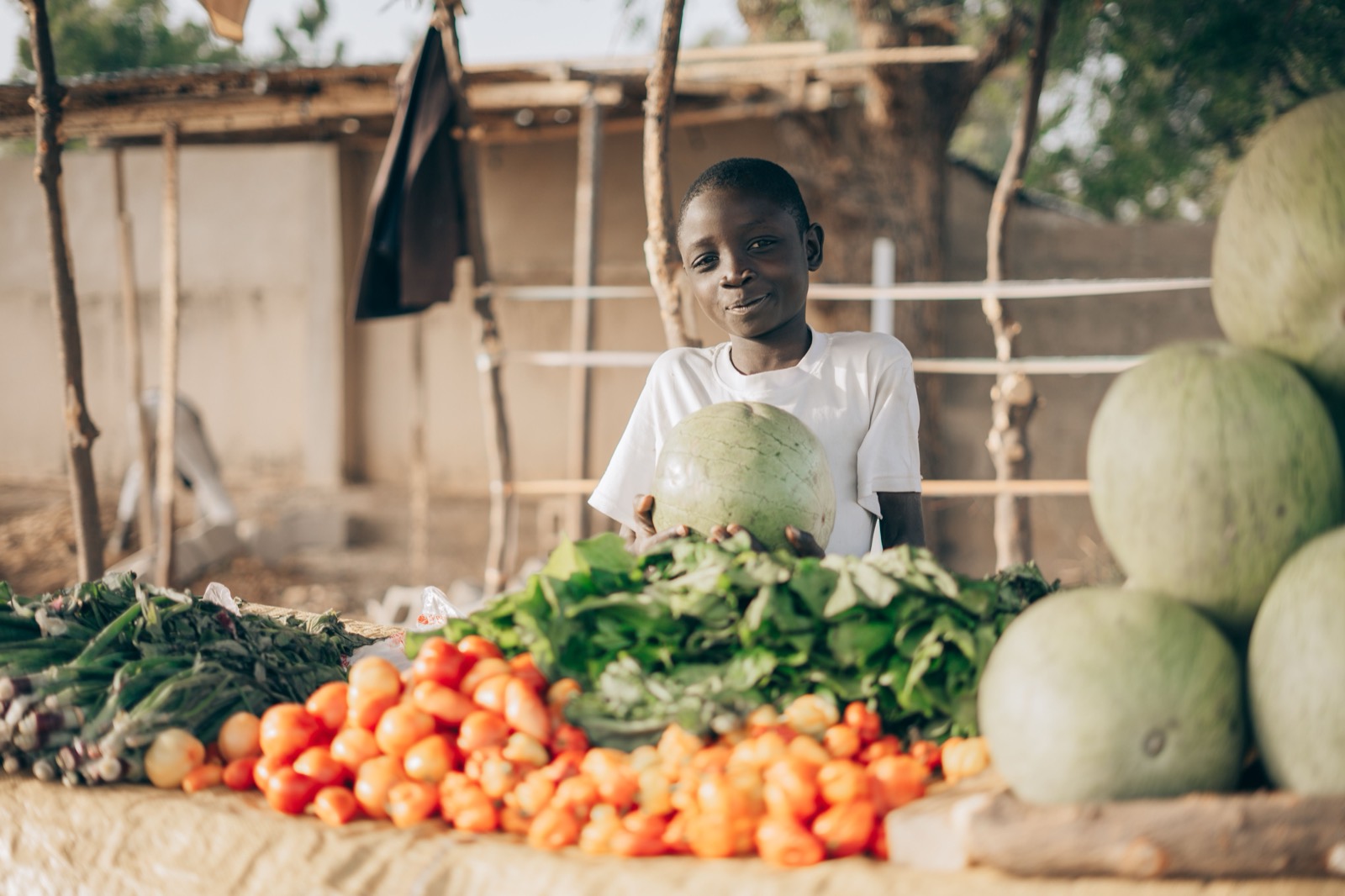 A market vendor with tomatoes and greens