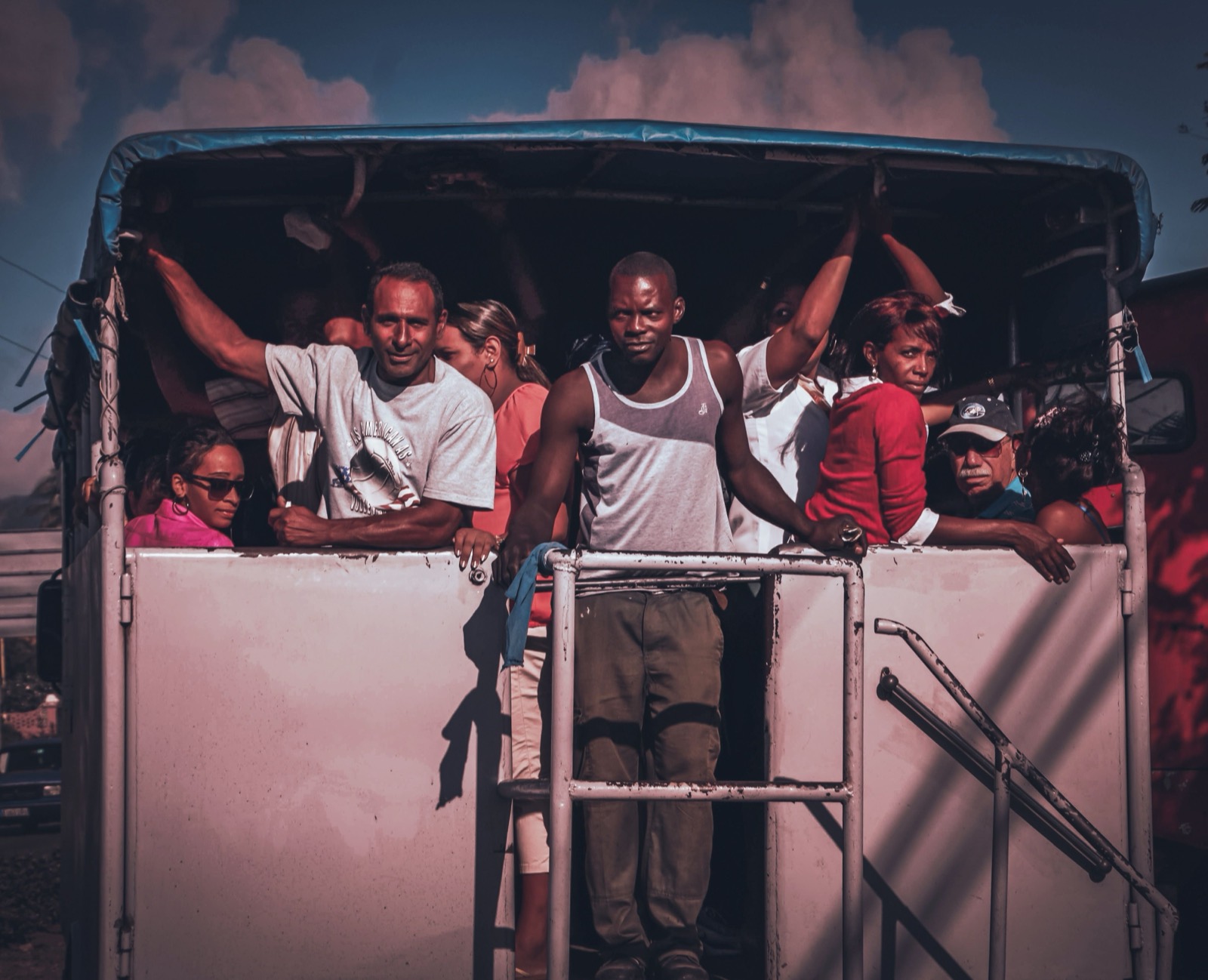 Riders crowd the back of a truck, looking out