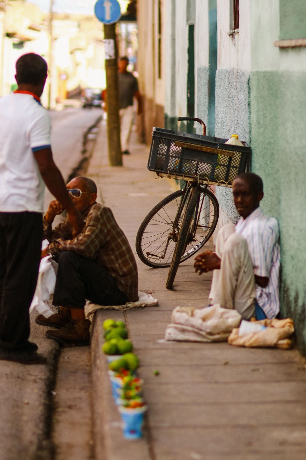 Two men sell limes from the sidewalk beside a bicycle