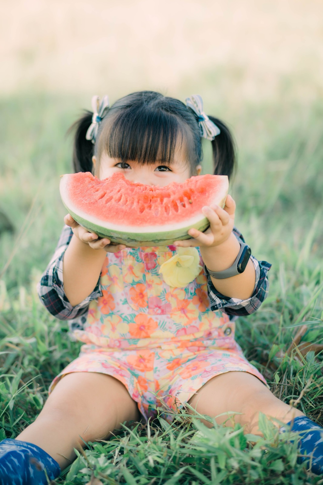 A toddler bites into a slice of watermelon