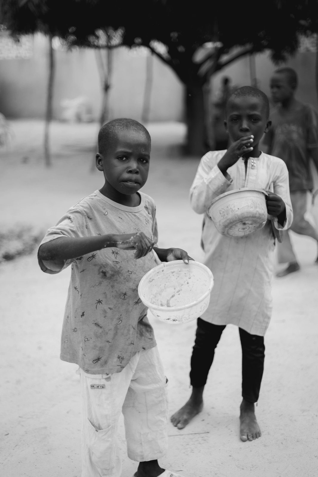 Two children hold out empty bowls, black and white